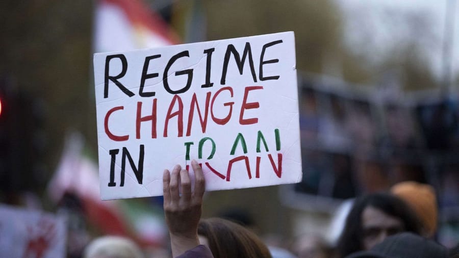 Protester holds sign saying "REGIME CHANGE in IRAN"
