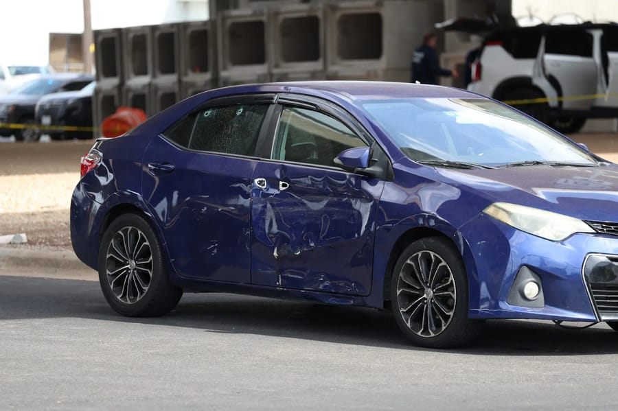 Bullet holes and car damage from a blue Toyota Corolla involved in the shooting.