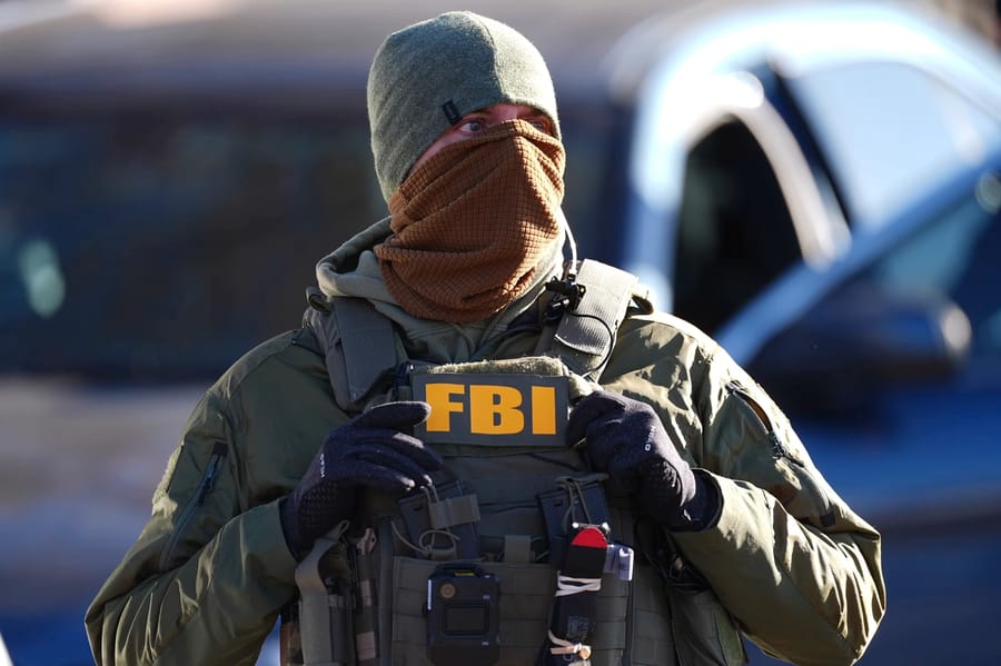 An FBI agent standing watch outside an apartment complex during an immigration raid Wednesday in Denver.